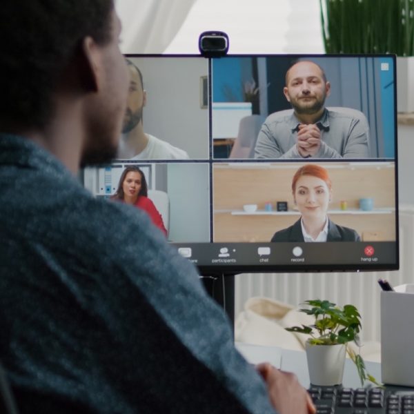 African american man waving to colleagues, talking on online conference internet call using webcam communication. Remote worker working from home keeping distance while using technology